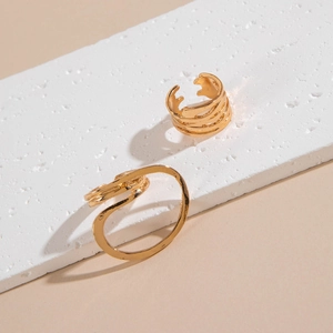 Macro detail of gold layered hollow rings with organic wavy lines and polished finish