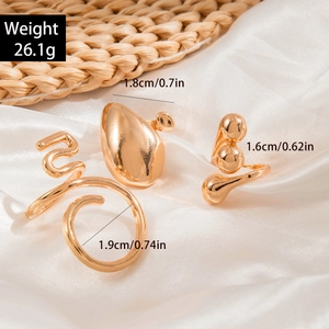 Detailed view of three gold-tone geometric rings showing sizes and weight on silk fabric