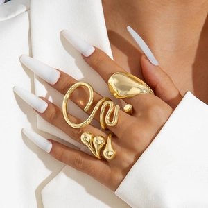 Detail of four-piece chunky gold irregular rings worn by a model in white attire