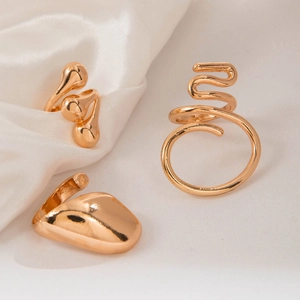Three-piece gold ring set featuring irregular geometric cutout designs on white silk fabric