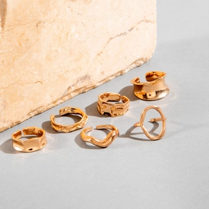 Close-up of a 6-piece set of gold irregular geometric rings with textured molten surfaces