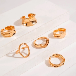 Detailed view of six gold irregular open rings with organic shapes on a white pedestal