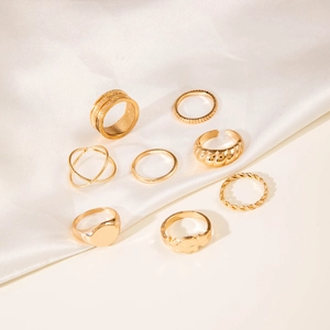 Close-up of 8-piece gold-toned minimalist stackable rings on white silk fabric