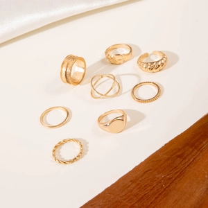 Detail of an eight-piece gold ring set with textured, smooth, and twisted designs