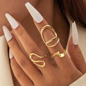 Detailed view of three minimalist gold irregular wavy rings worn on a model hand