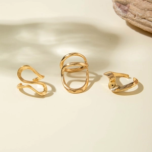 Detailed view of three minimalist gold-plated irregular hollow rings on beige background