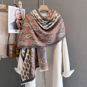 Detail of paisley pattern winter scarf with short tassels layered on an elegant coat