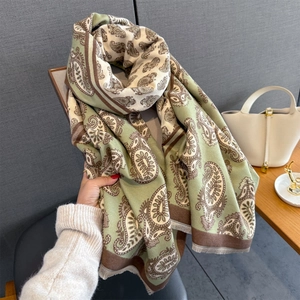 Detail of green and brown paisley pattern scarf with soft fringe trim texture