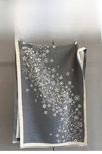 Détail de l'imprimé fleuri et flocon sur une écharpe gris foncé avec bords à franges