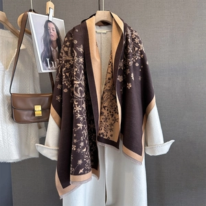 Châle fleuri en marron et kaki avec franges, présenté sur un manteau en laine chic