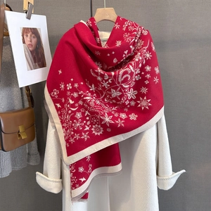 Détail d'une écharpe en maille florale rouge avec pompons sur un manteau d'hiver