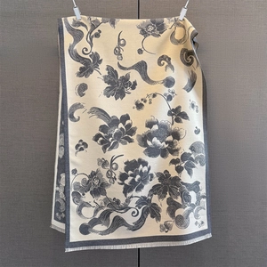 Detail of floral printed winter scarf with fringe edges in beige and dark gray
