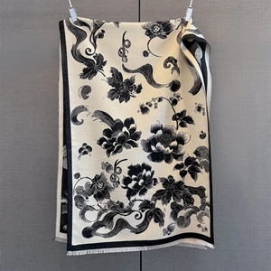 Close-up of winter scarf with black floral print, fringed edges and soft white base