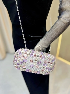 Close-up of rectangular evening bag with purple and pink rhinestones and silver chain
