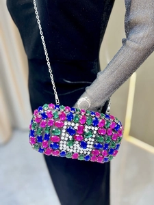 Detail of evening clutch with colorful gemstones and rhinestone ring handle decoration