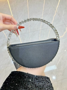 Detail view of black crescent evening bag with rhinestone handle and mesh fringe