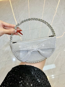 Detail of silver rhinestone bow evening bag featuring a crystal-encrusted top handle