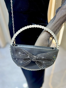 Detail of evening bag featuring crystal bow, rhinestone ring handle and silver chain