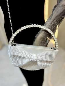 Detail of silver evening bag featuring large rhinestone bow and crystal handle