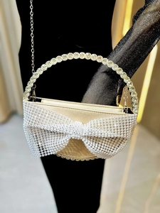 Detailed view of luxury evening bag with oversized rhinestone bow and crystal ring handle