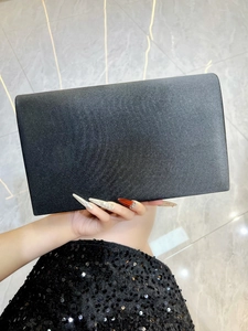 Gros plan d'une pochette de soirée en satin noir avec rabat épuré et texture mate élégante