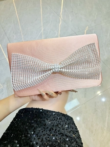 Vue détaillée de la pochette en satin avec un nœud serti de cristaux sur tissu champagne