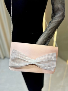 Détail du sac de soirée en satin rose avec nœud en strass étincelant et bandoulière chaîne