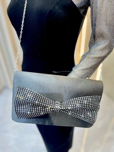 Détail du sac de soirée pailleté avec un grand nœud en strass et bandoulière chaîne