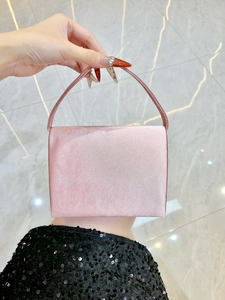 Détail d'une pochette de soirée élégante en satin rose tenue devant un sol en marbre