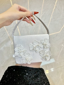Détail du sac de soirée en satin argenté avec fleurs en dentelle 3D et perles blanches