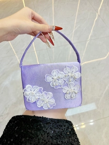 Détail d'un sac de soirée en satin violet avec fleurs en dentelle blanche et perles