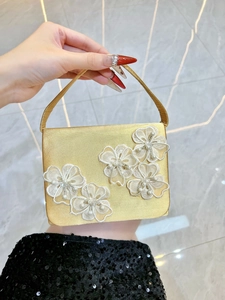 Détail de pochette en satin doré avec fleurs en dentelle 3D et centres en perles