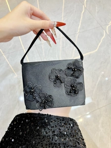 Détail d'un sac à main en satin noir avec fleurs 3D en dentelle et perles