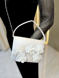 Détail du sac de soirée en satin blanc avec fleurs en dentelle, perles et bandoulière chaîne