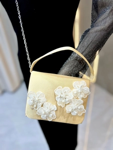 Détail du sac de soirée en satin doré avec fleurs en dentelle blanche et perles