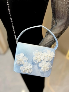 Détail du sac de soirée en satin bleu clair avec fleurs en dentelle et perles