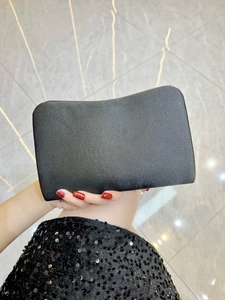 Detailed view of the smooth black satin texture and elegant curved top of the evening clutch