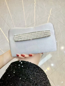 Detailed view of silver satin evening clutch with rows of pearls and rhinestone trim