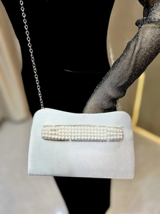 Detailed view of white satin evening clutch with elegant pearl and rhinestone trim stripes