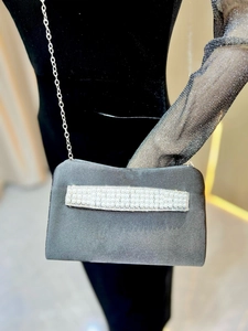 Detailed shot of black satin evening clutch featuring elegant pearl and rhinestone accents