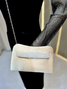 Detail of elegant champagne satin clutch bag with pearls and rhinestones on a metal chain