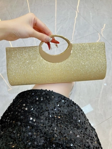 Detail of glitter gold clutch bag with metallic ring handle for elegant evening party