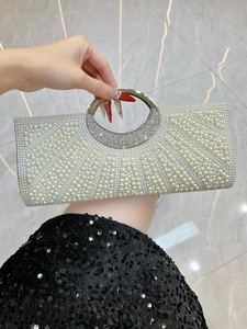 Detail of elegant evening clutch with faux pearls, rhinestones, and round metal handle
