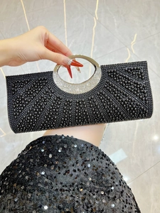 Detail of black rhinestone evening clutch with crystal embellished circular metal handle