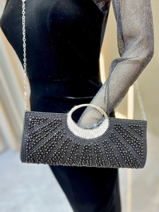 Detail of black evening clutch with beaded texture and crystal-encrusted metal handle