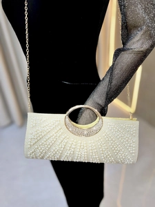 Detail of elegant off-white evening bag with pearls, rhinestones and golden round handle