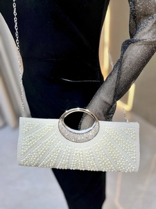 Detail of elegant pearl evening bag with silver circular handle and sparkly rhinestone accents