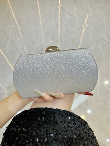 Close-up of silver glitter evening clutch bag with gold clasp and curved hard shell