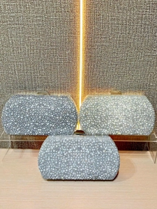 Elegant evening clutch bags with pearls and rhinestones on a wooden stand in various colors
