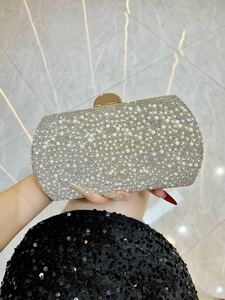 Detail of the pearly evening clutch with rhinestones and a gold metal clasp handle